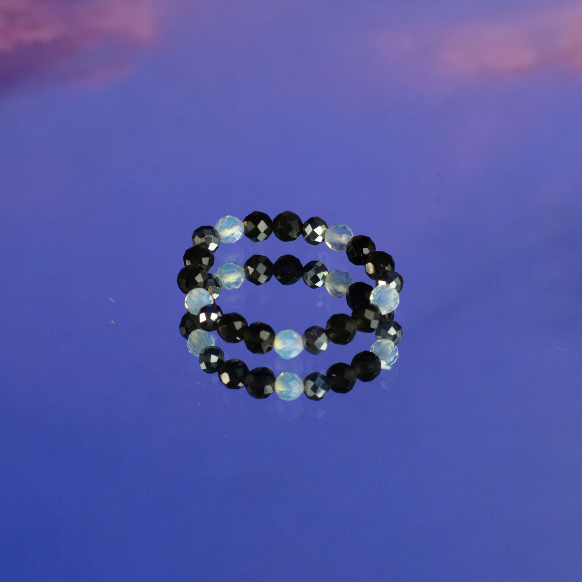 Mystical Nymph Spirit Gemstone 3 Ring Set - Full Moon, two black beaded rings stacked on a blue and purple surface, by Quintessential Holistic Health Ltd