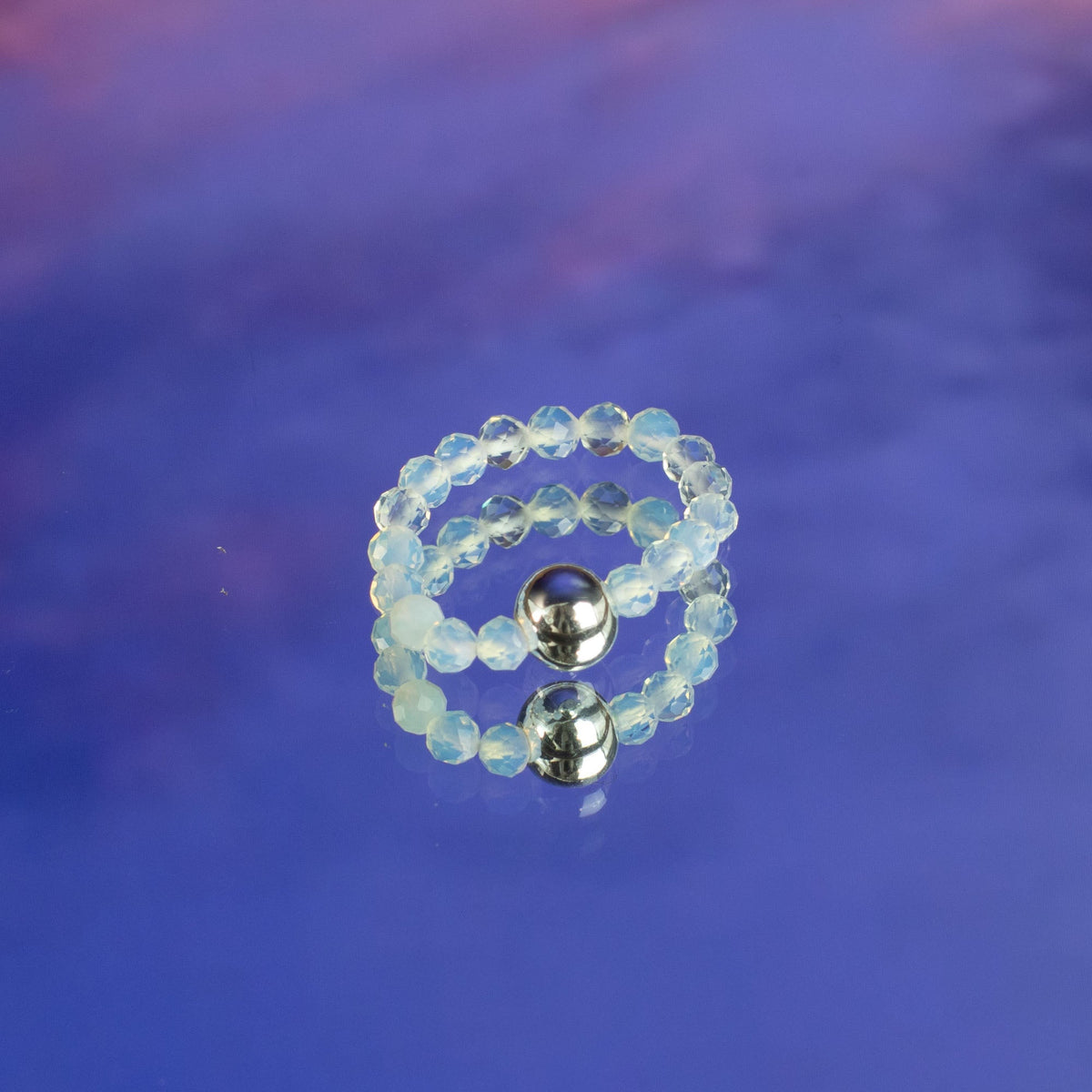 Mystical Nymph Spirit Gemstone 3 Ring Set - Full Moon, pale translucent beaded rings stacked on a blue and purple surface, by Quintessential Holistic Health Ltd