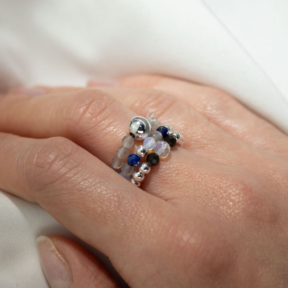 Mystical Nymph Spirit Gemstone 3-Ring Set – Northern Lights, blue, grey and silver-toned beaded rings worn stacked on a hand, by Quintessential Holistic Health Ltd