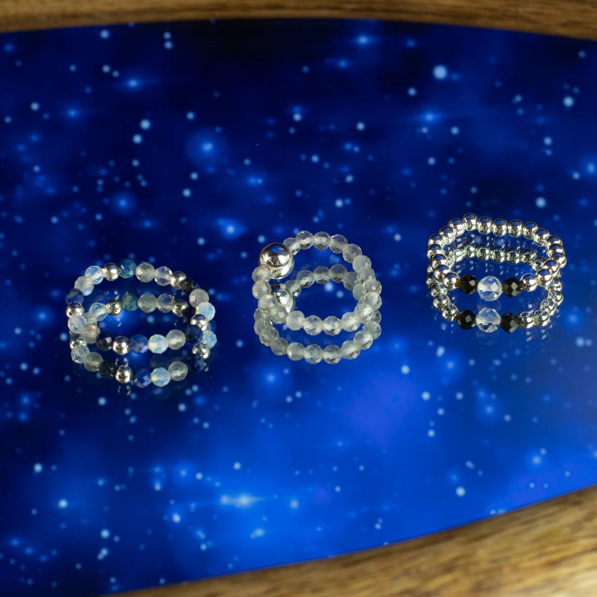 Mystical Nymph Spirit Gemstone 3 Ring Set - Northern Lights shown together against a starry blue scene by Quintessential Holistic Health Ltd
