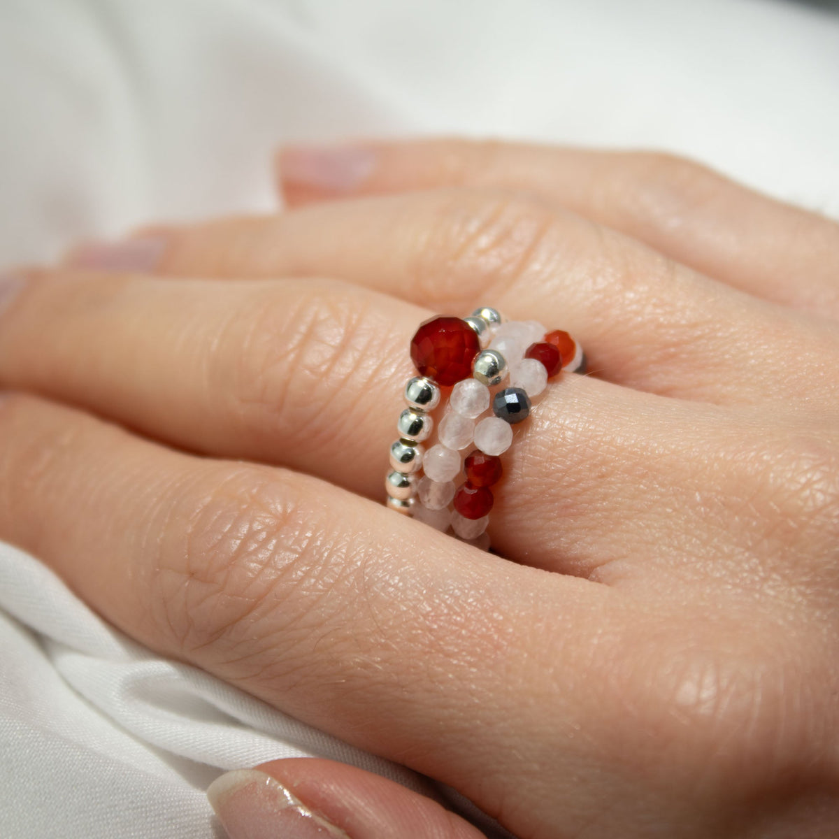 Mystical Nymph Spirit Gemstone 3-Ring Set – Love & Flame, red, white and silver-toned beaded rings worn stacked on a hand, by Quintessential Holistic Health Ltd