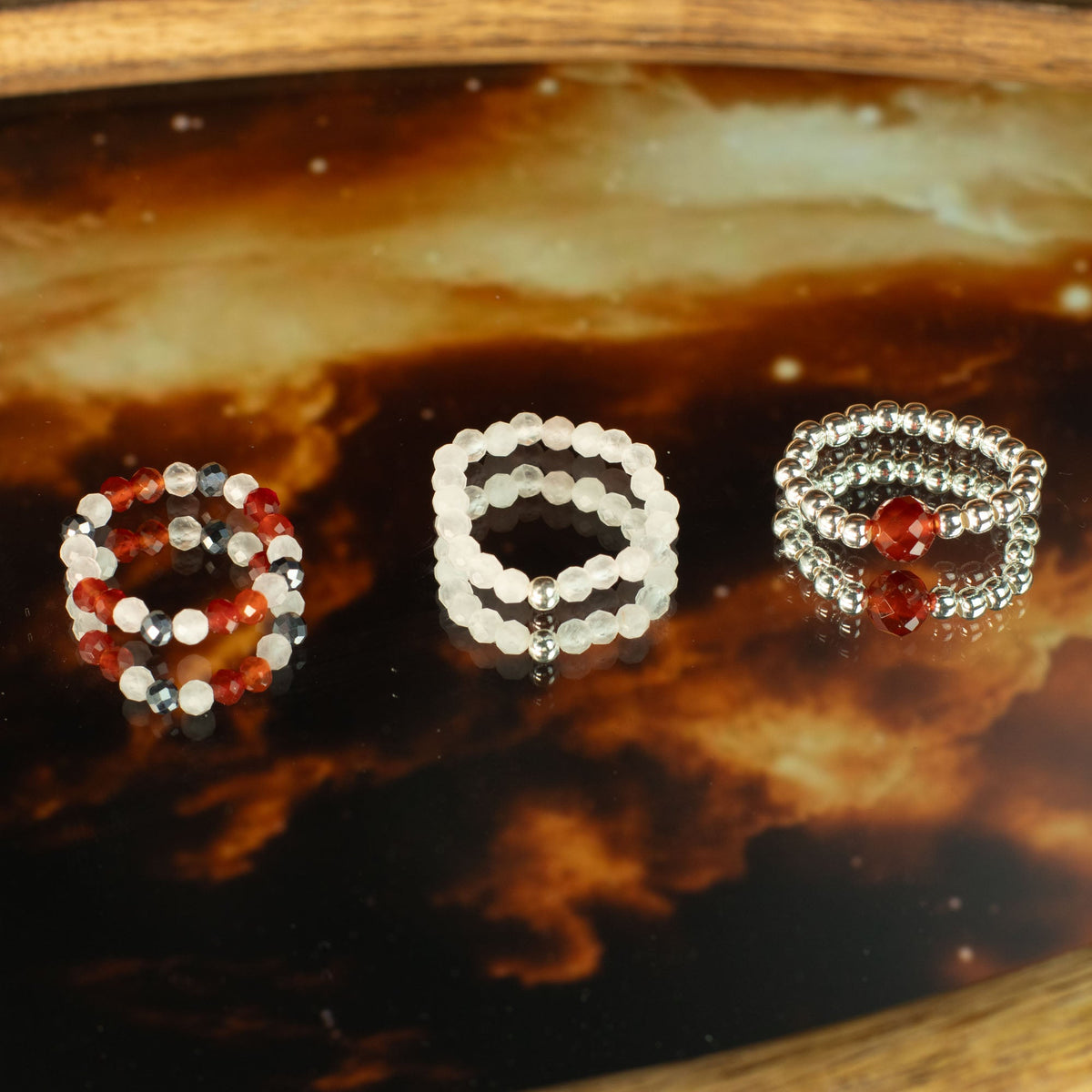 Mystical Nymph Spirit Gemstone 3 Ring Set - Love and Flame shown together on a dark amber patterned surface by Quintessential Holistic Health Ltd