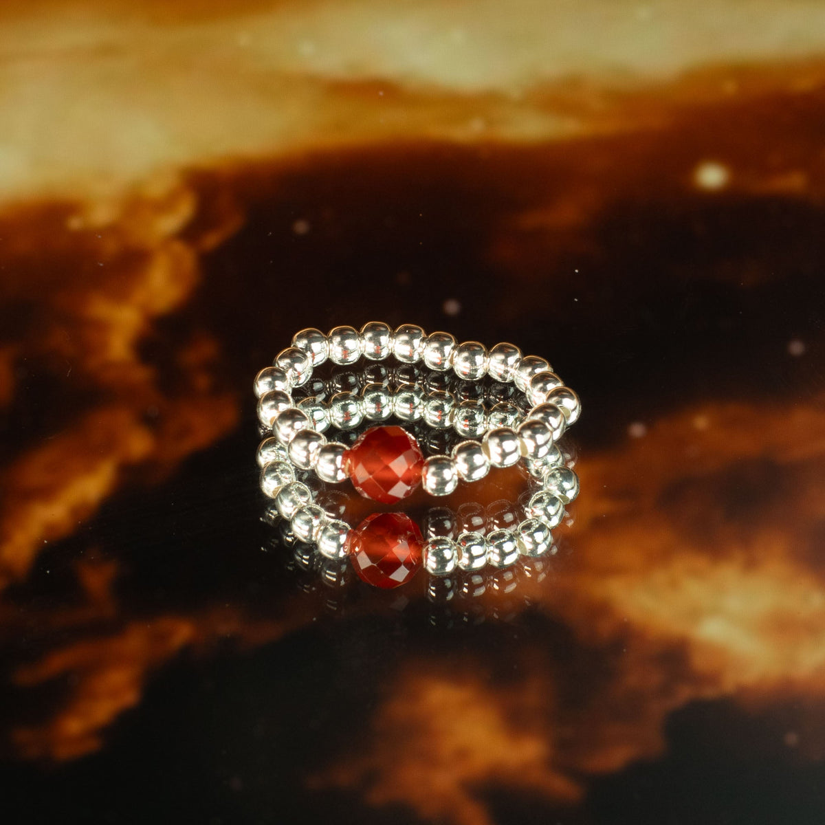 Mystical Nymph Spirit Gemstone 3 Ring Set - Love and Flame with silver-tone and red beads on a dark amber surface by Quintessential Holistic Health Ltd
