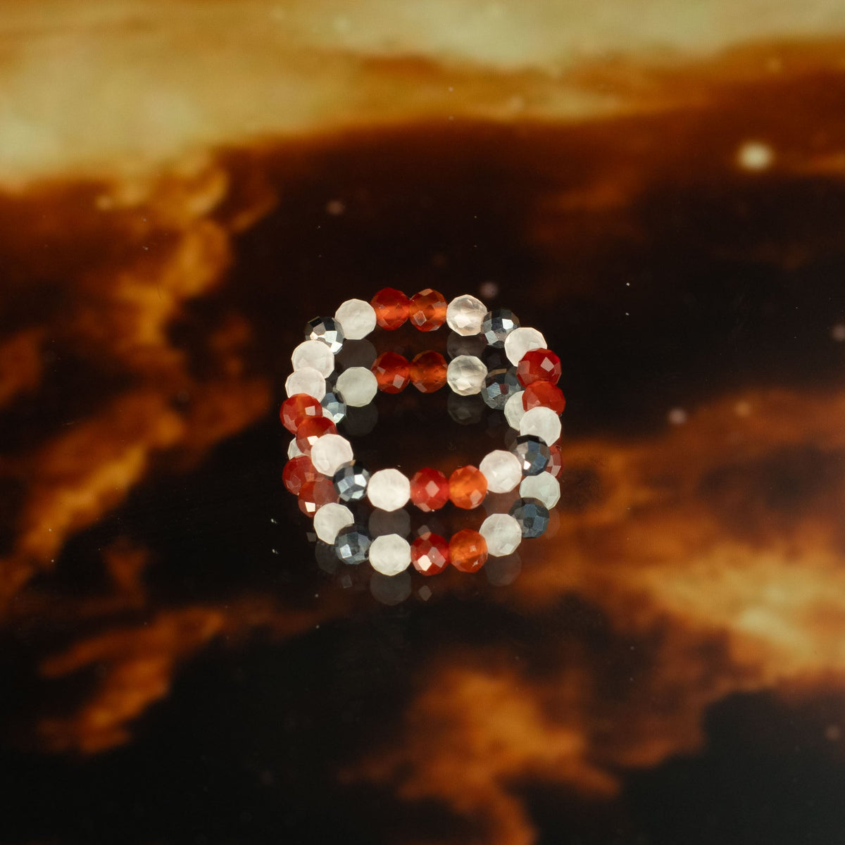Mystical Nymph Spirit Gemstone 3-Ring Set – Love & Flame, red, black, white and silver-toned beaded rings stacked on a dark amber surface, by Quintessential Holistic Health Ltd
