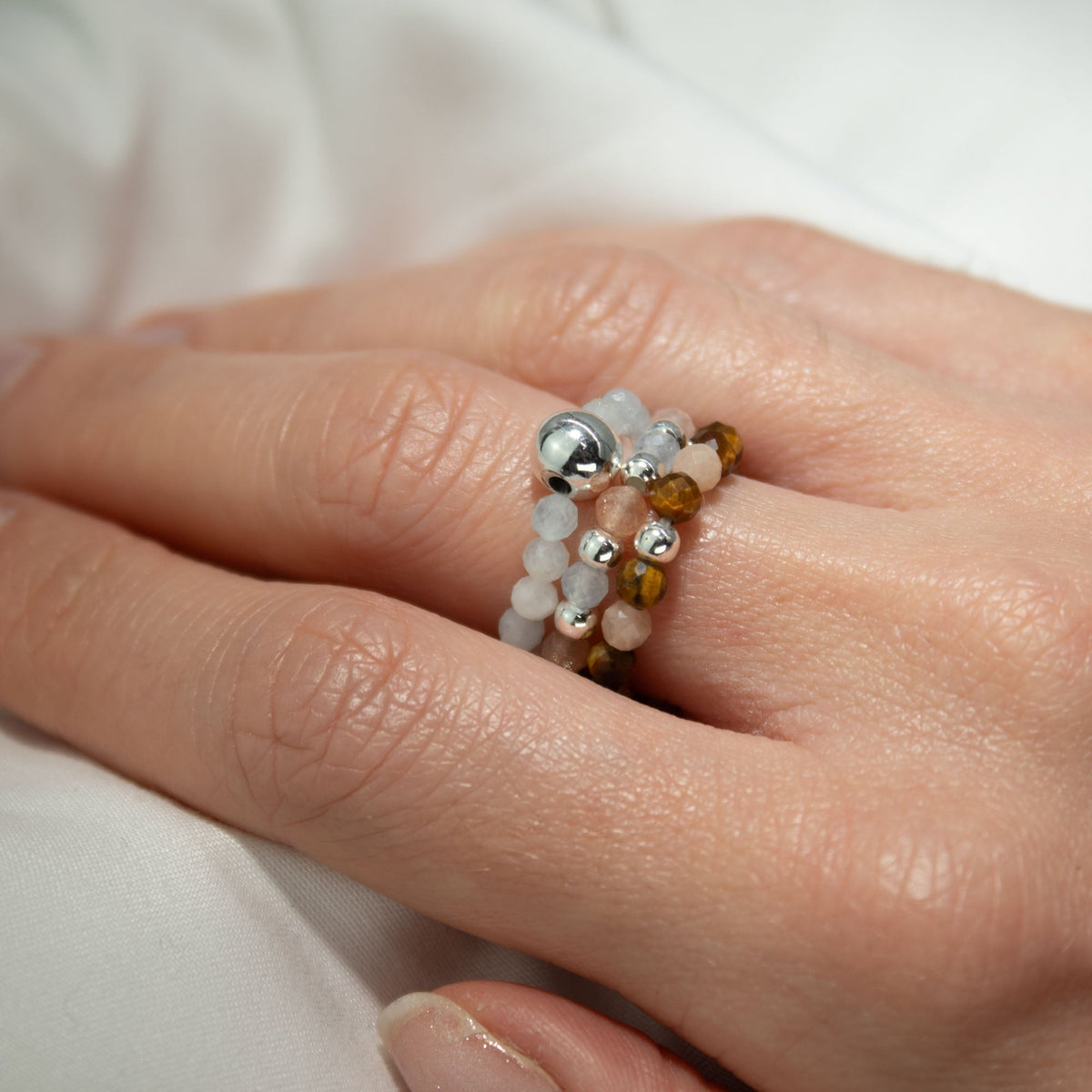 Mystical Nymph Spirit Gemstone 3-Ring Set – Sea Sunset worn together on a finger with peach, brown, pale blue and silver-tone beads by Quintessential Holistic Health Ltd