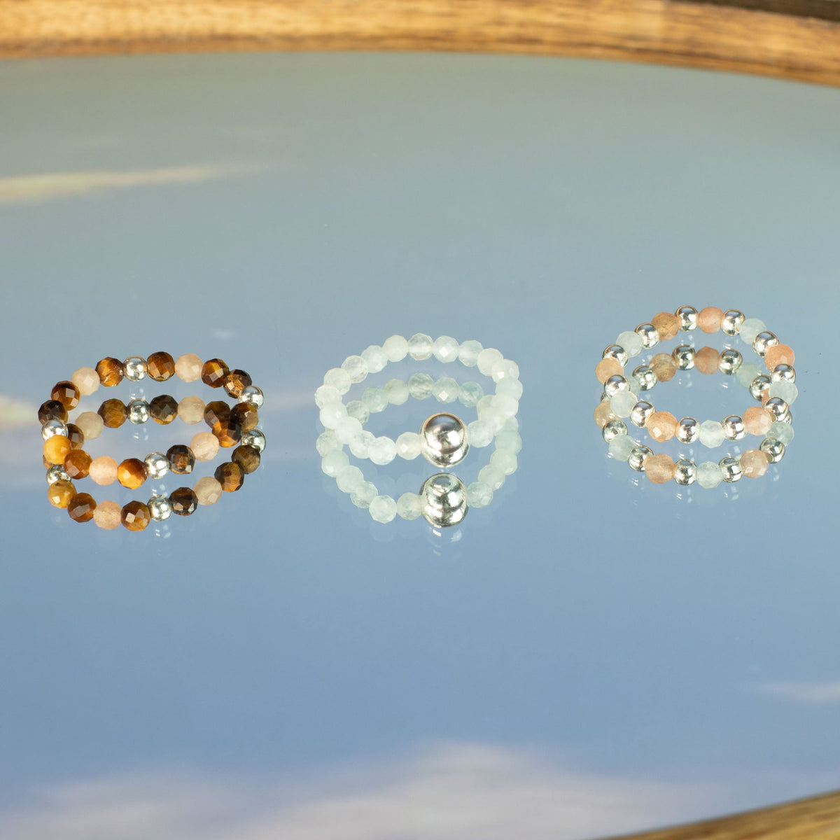 Mystical Nymph Spirit Gemstone 3-Ring Set – Sea Sunset shown as three rings together on a reflective pale blue surface by Quintessential Holistic Health Ltd