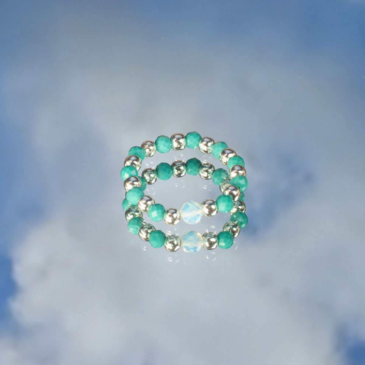 Mystical Nymph Spirit Gemstone 3-Ring Set – Endless Ocean, turquoise and pale beaded rings stacked on a cloudy blue surface by Quintessential Holistic Health Ltd