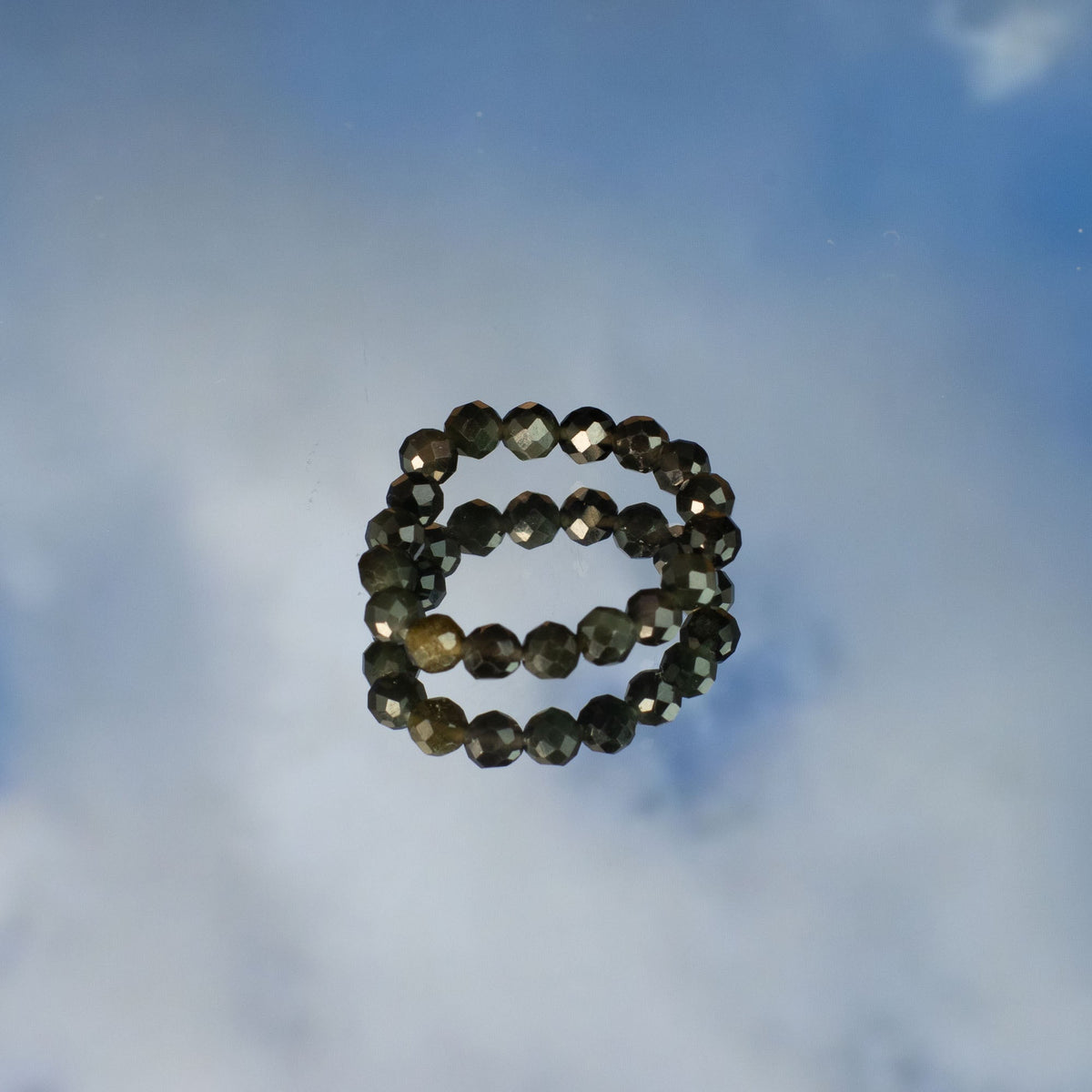 Mystical Nymph Spirit Gemstone 3-Ring Set – Endless Ocean, two dark beaded rings stacked on a cloudy blue surface by Quintessential Holistic Health Ltd