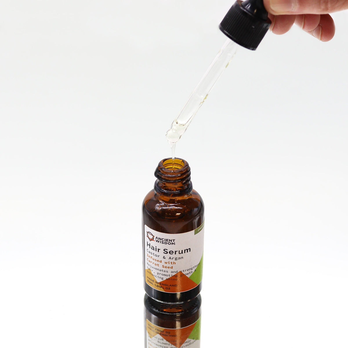 Organic Vegan-Friendly Carrot Seed Hair Serum - 30ml, with a glass dropper held above the open brown bottle, by Quintessential Holistic Health Ltd