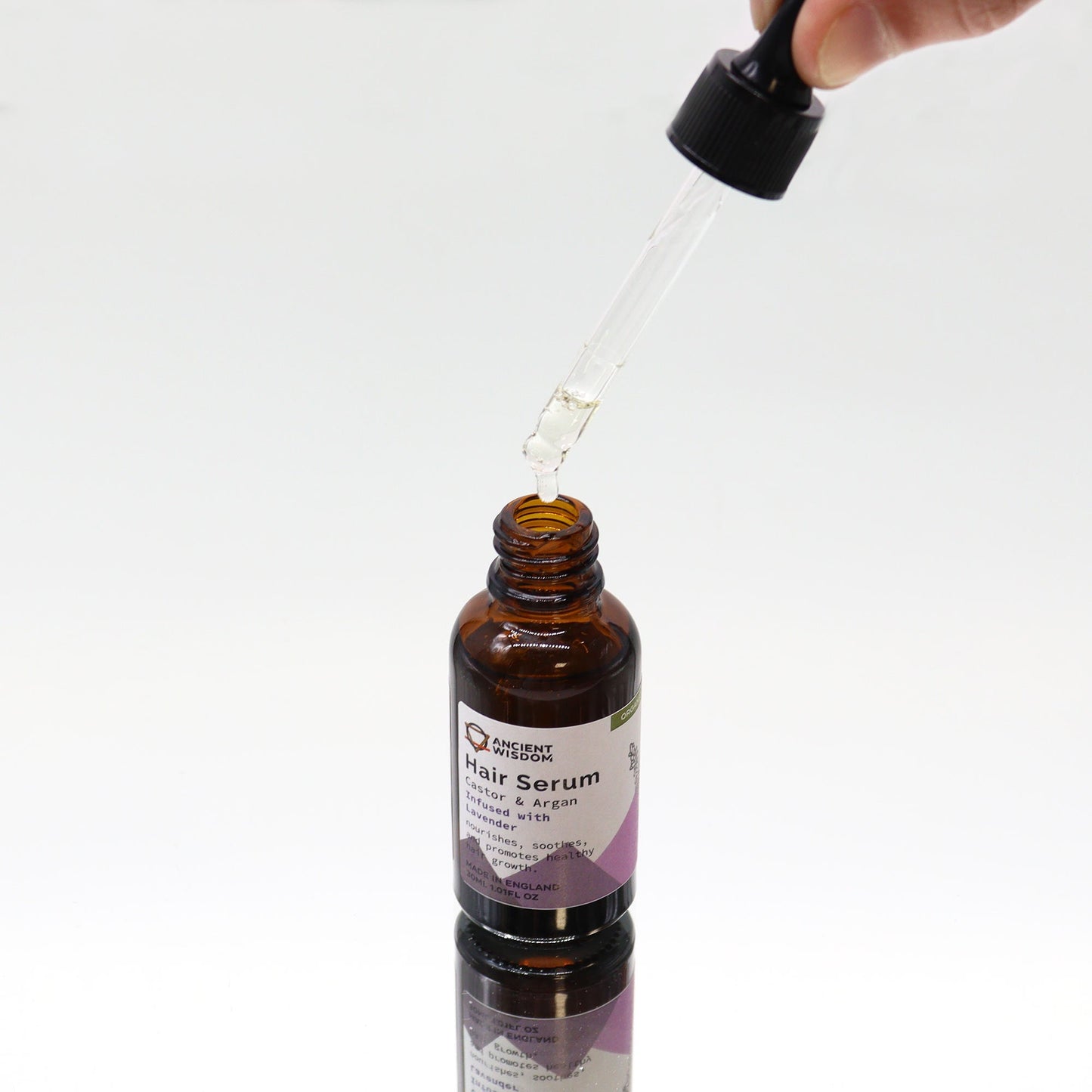 Organic Vegan-Friendly Lavender Hair Serum - 30ml, open amber bottle beneath a raised glass dropper, by Quintessential Holistic Health Ltd