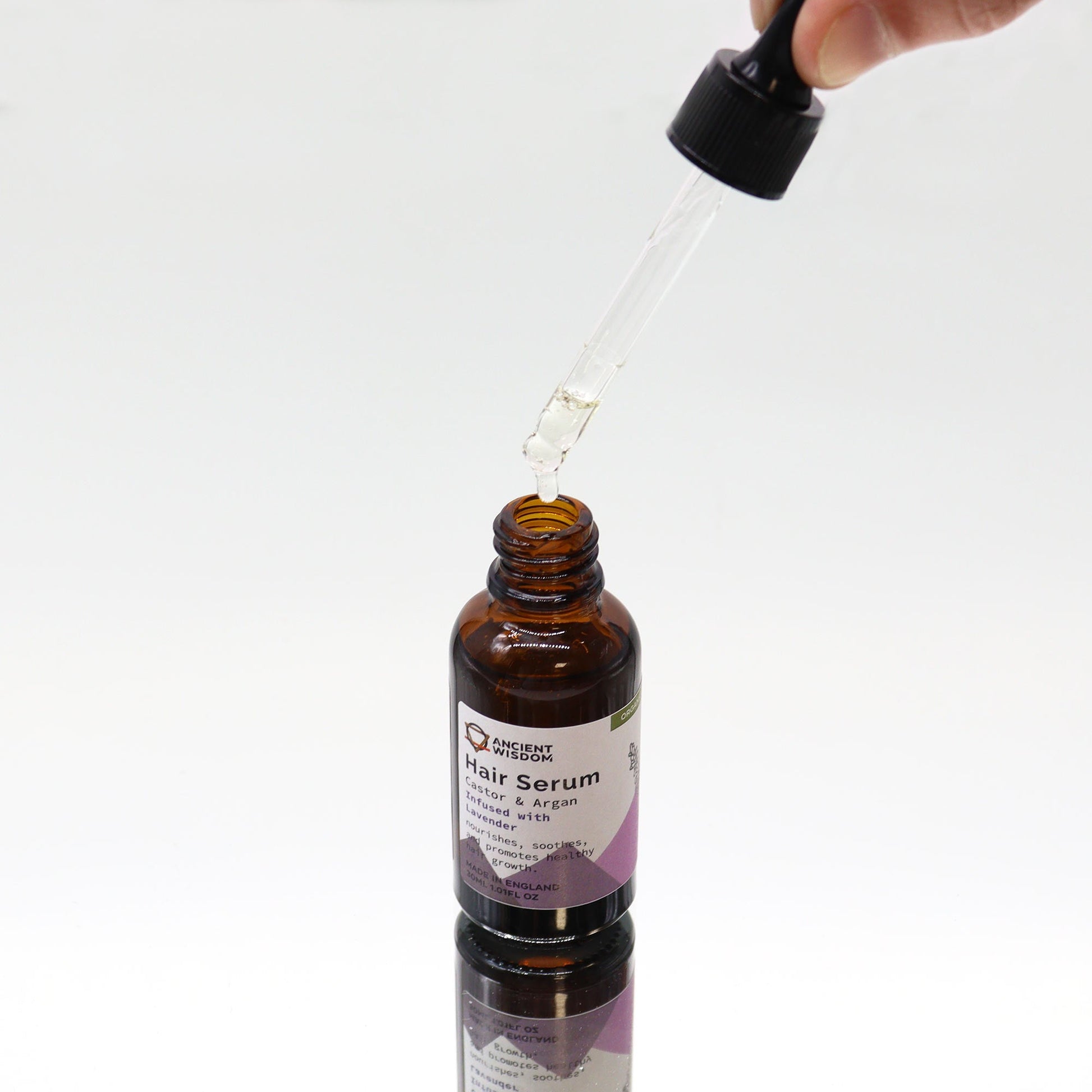 Organic Vegan-Friendly Lavender Hair Serum - 30ml, open amber bottle beneath a raised glass dropper, by Quintessential Holistic Health Ltd