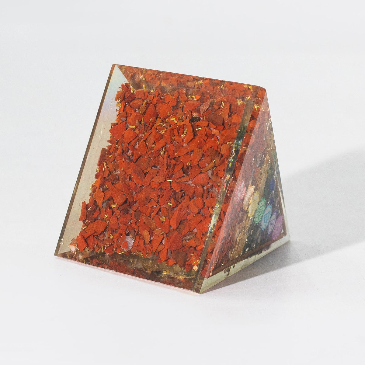 Orgonite Paperweight - Medium 7 Chakra Copper Pyramid, showing a dense red-chip face and multicoloured side layers by Quintessential Holistic Health Ltd