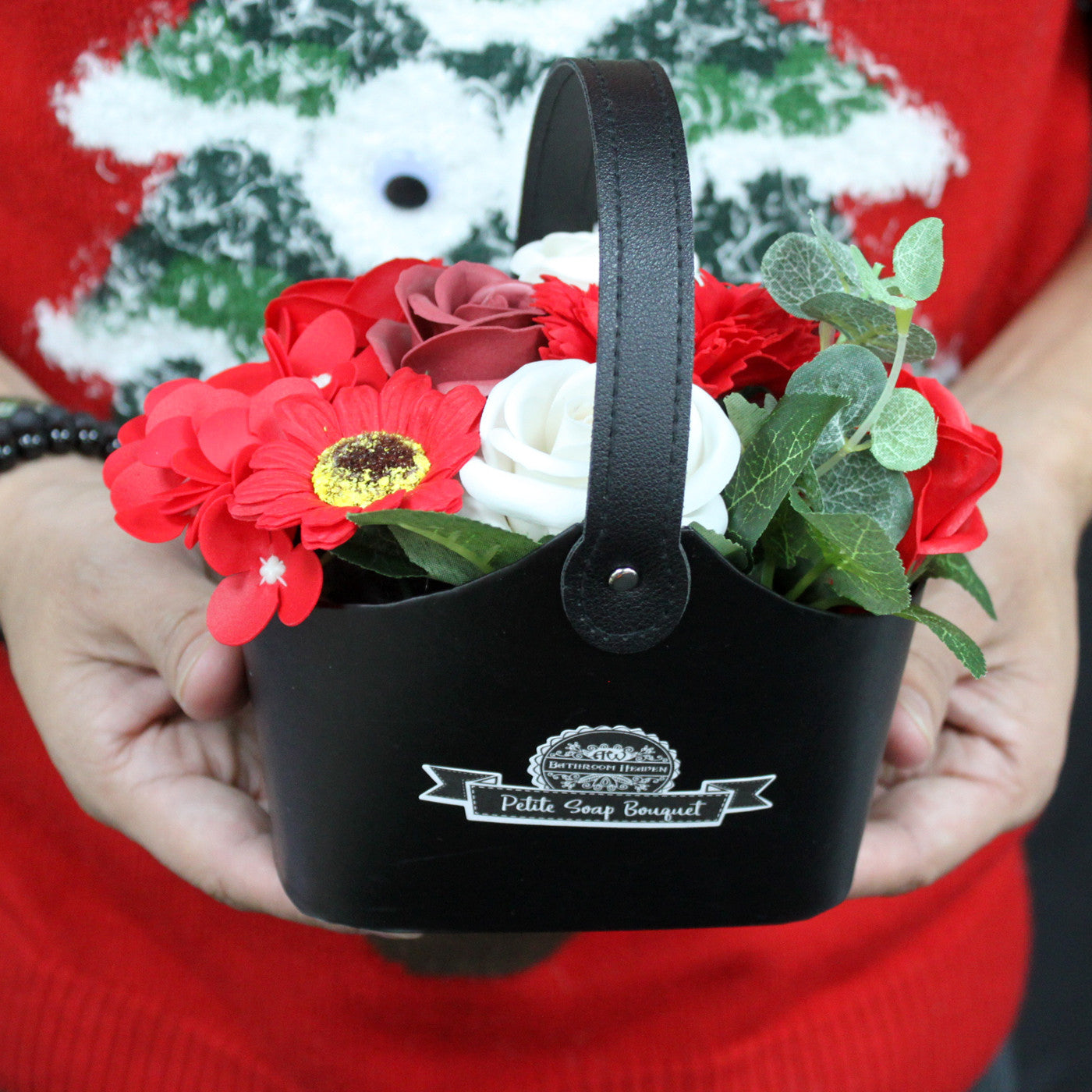 Petite Bouquet Basket - Rich Reds, a compact red and white floral arrangement in a black basket held in both hands, by Quintessential Holistic Health Ltd