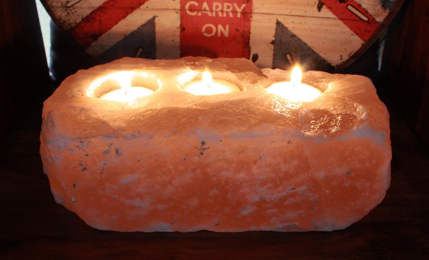 Himalayan Salt Crystal Candle Holder - Natural Rectangular Triple with three lit candles in a rough pink block by Quintessential Holistic Health Ltd