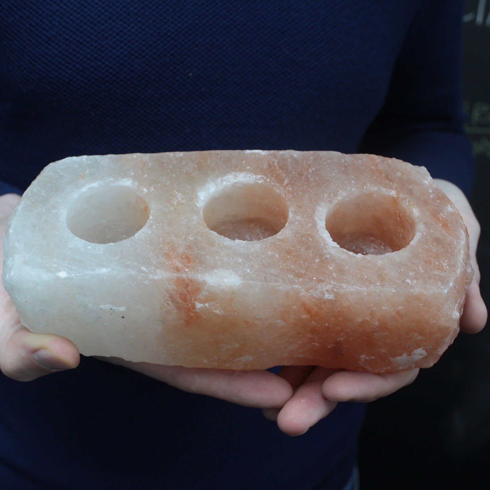 Himalayan Salt Crystal Candle Holder - Natural Rectangular Triple held in two hands with three empty circular recesses by Quintessential Holistic Health Ltd