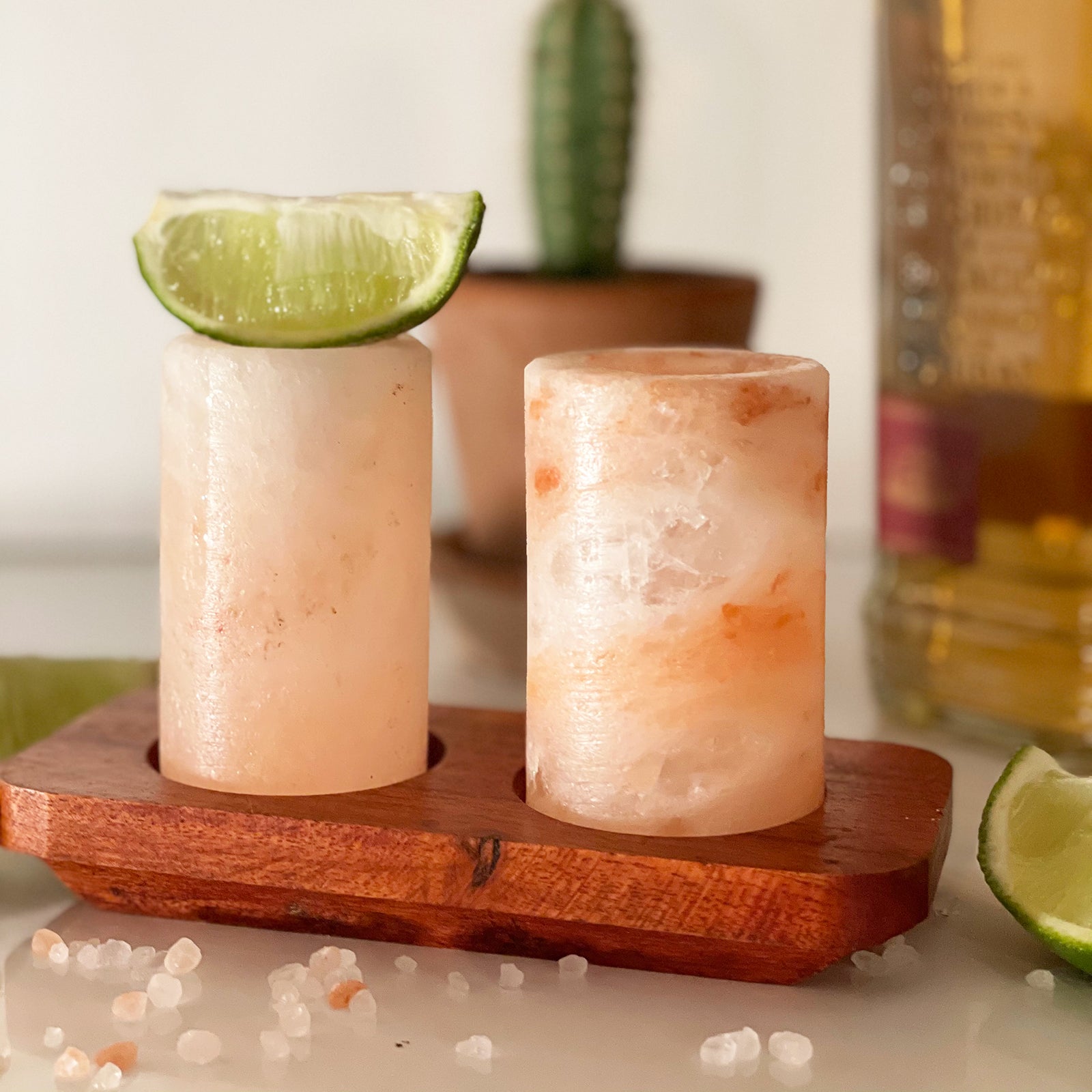 Set of 2 Hand-Carved Himalayan Salt Shot Glasses & Wooden Tray, two glowing pink marbled glasses on a red-brown tray with a lime wedge by Quintessential Holistic Health Ltd