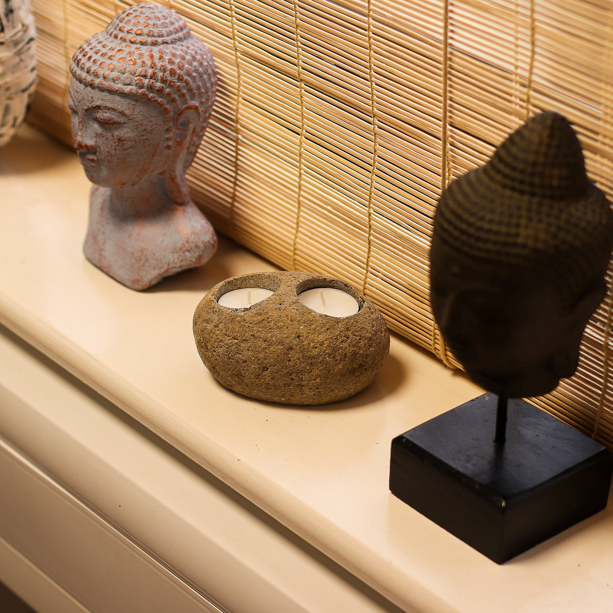Natural Riverstone Tea Light Holder - Double, small rounded stone with two tea light recesses displayed between sculptures by Quintessential Holistic Health Ltd