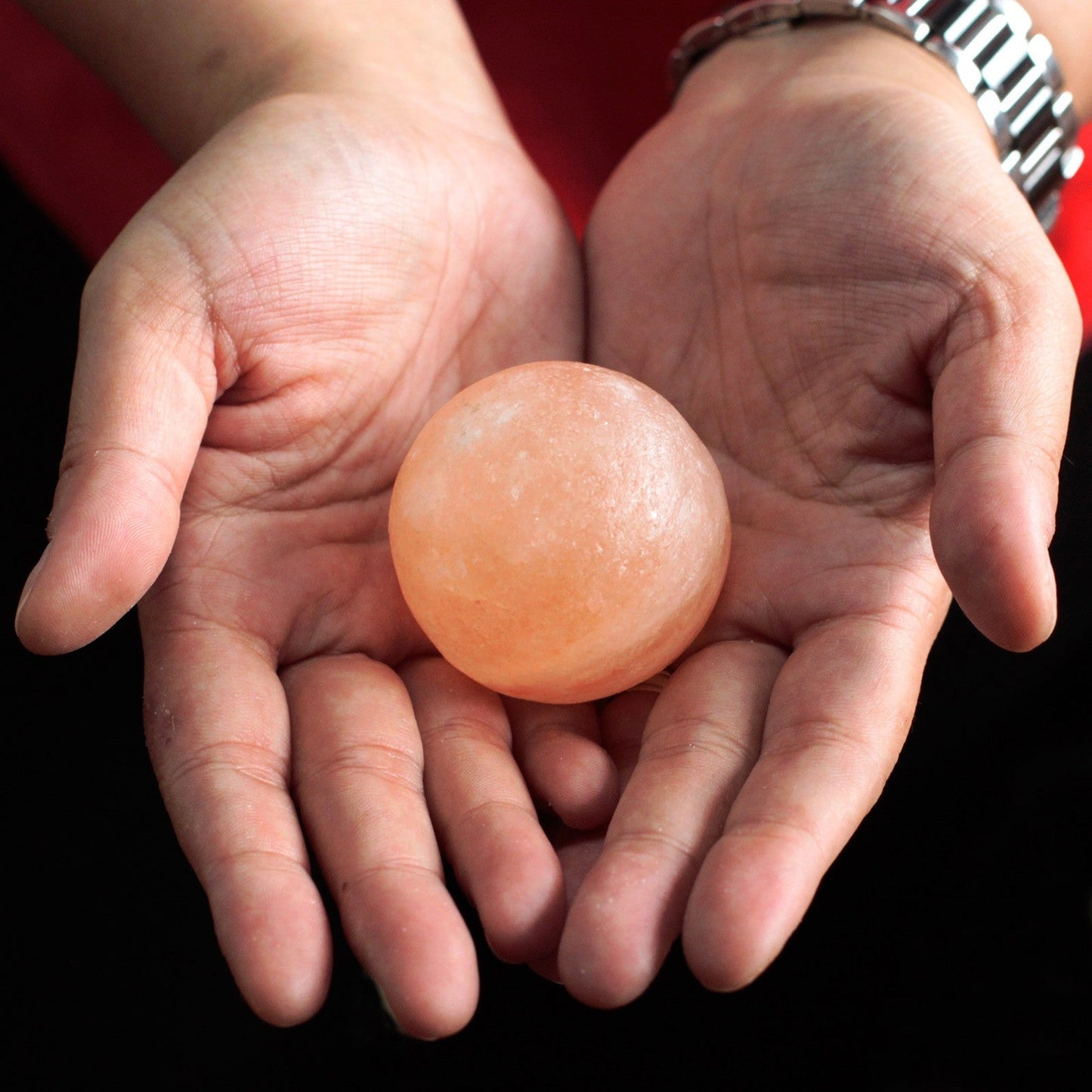 Himalayan Salt Deodorant & Massage Stones - 3 Pack - Ball with a smooth peach-coloured sphere resting in two open hands by Quintessential Holistic Health Ltd