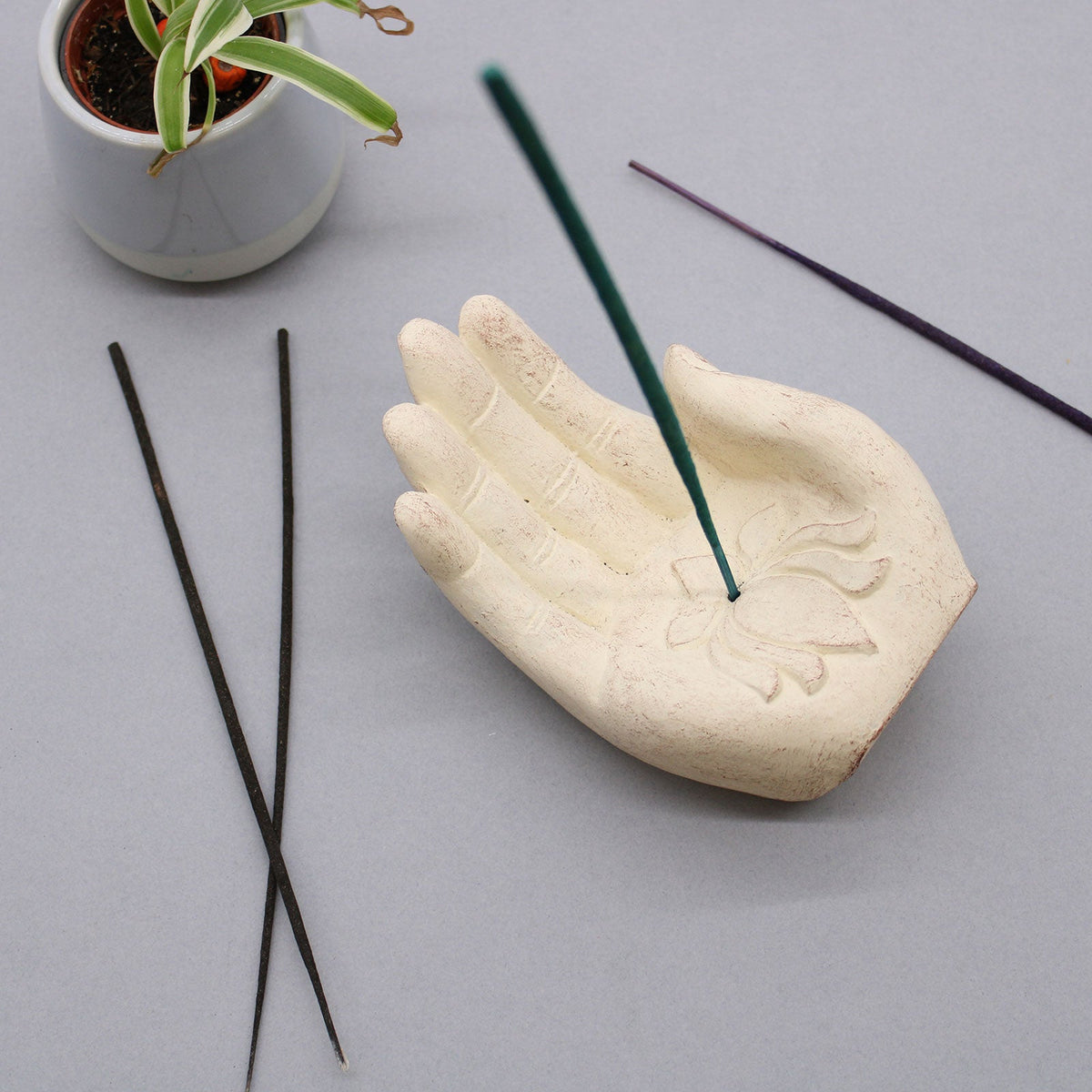 Concrete Incense Burner - Lotus - Purity and Rebirth - White, open palm holding a green stick beside four dark sticks, by Quintessential Holistic Health Ltd