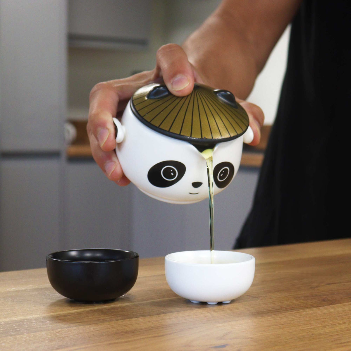 Kung Fu Panda Teapot Set - 2 Cups, Black/White, Orange Case, 210 ml pouring pale tea into a white cup, by Quintessential Holistic Health Ltd
