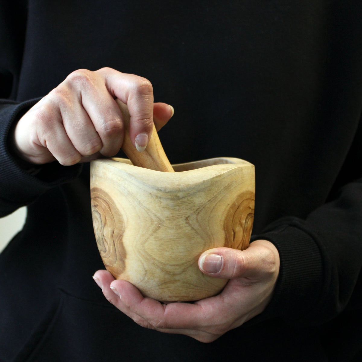 Ergo Teak Pestle & Mortar - Large held in both hands with the pestle inside the rounded wooden bowl by Quintessential Holistic Health Ltd