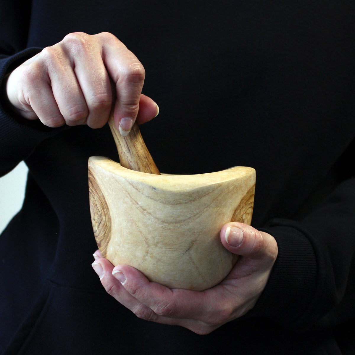 Ergo Teak Pestle & Mortar - Medium, held in both hands while the pestle is pressed inside the bowl by Quintessential Holistic Health Ltd