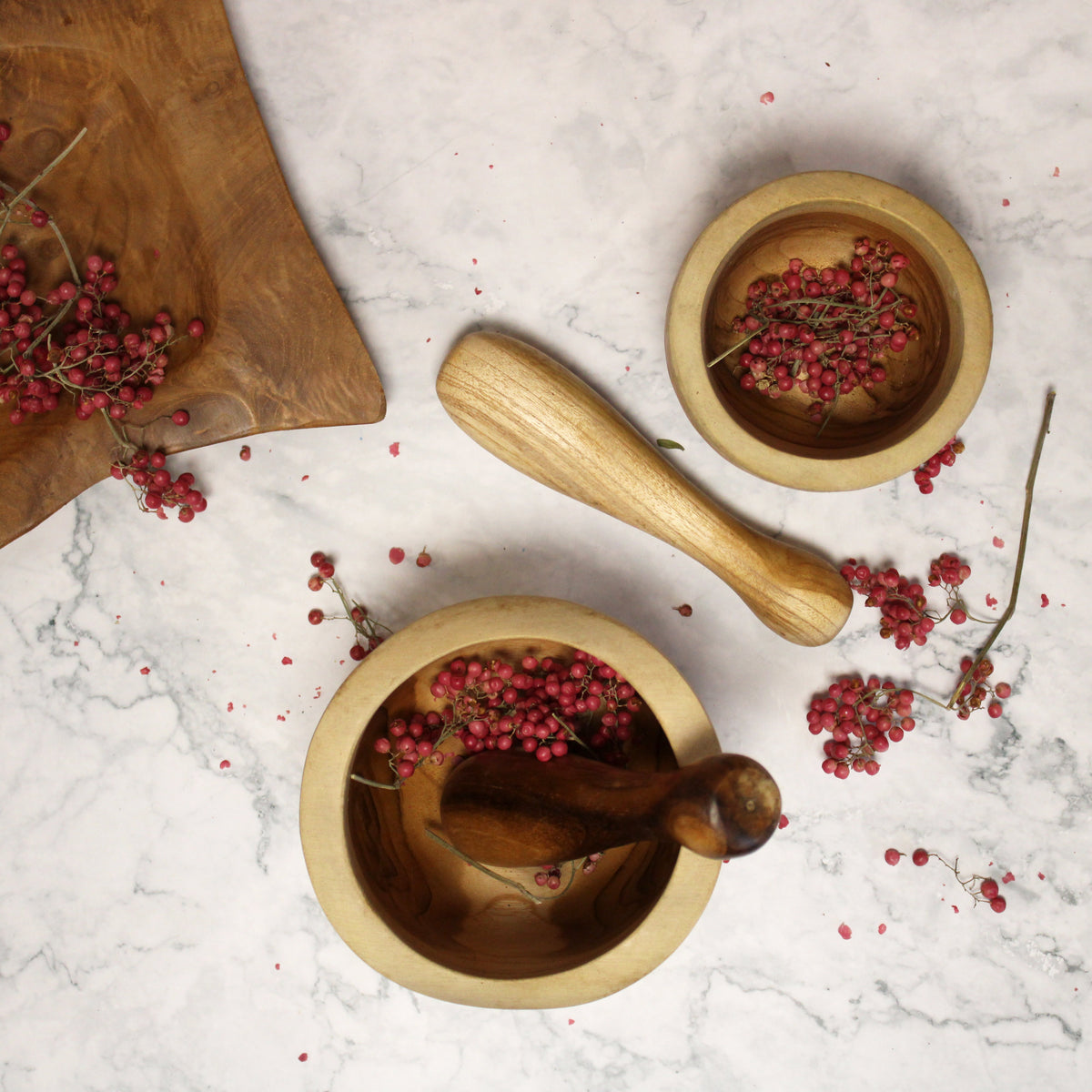 Ergo Teak Pestle & Mortar - Small, two wooden sets viewed from above among scattered pink peppercorns by Quintessential Holistic Health Ltd