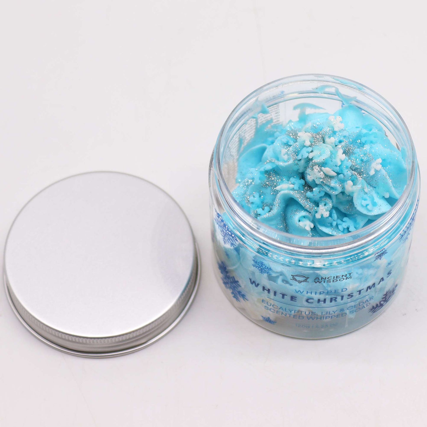 Vegan-Friendly Whipped Soap - White Christmas - 120g, open clear jar beside its silver lid, showing blue piped swirls by Quintessential Holistic Health Ltd