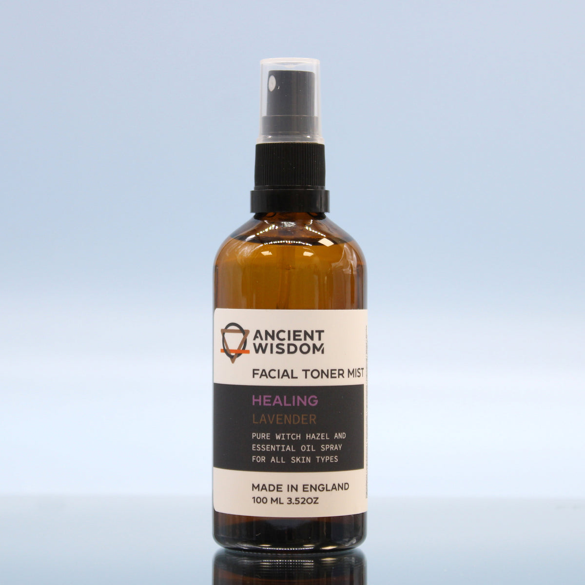 100ml Vegan-Friendly Witch Hazel Facial Toner Mist - Lavender in an amber spray bottle standing on a reflective block against pale blue by Quintessential Holistic Health Ltd