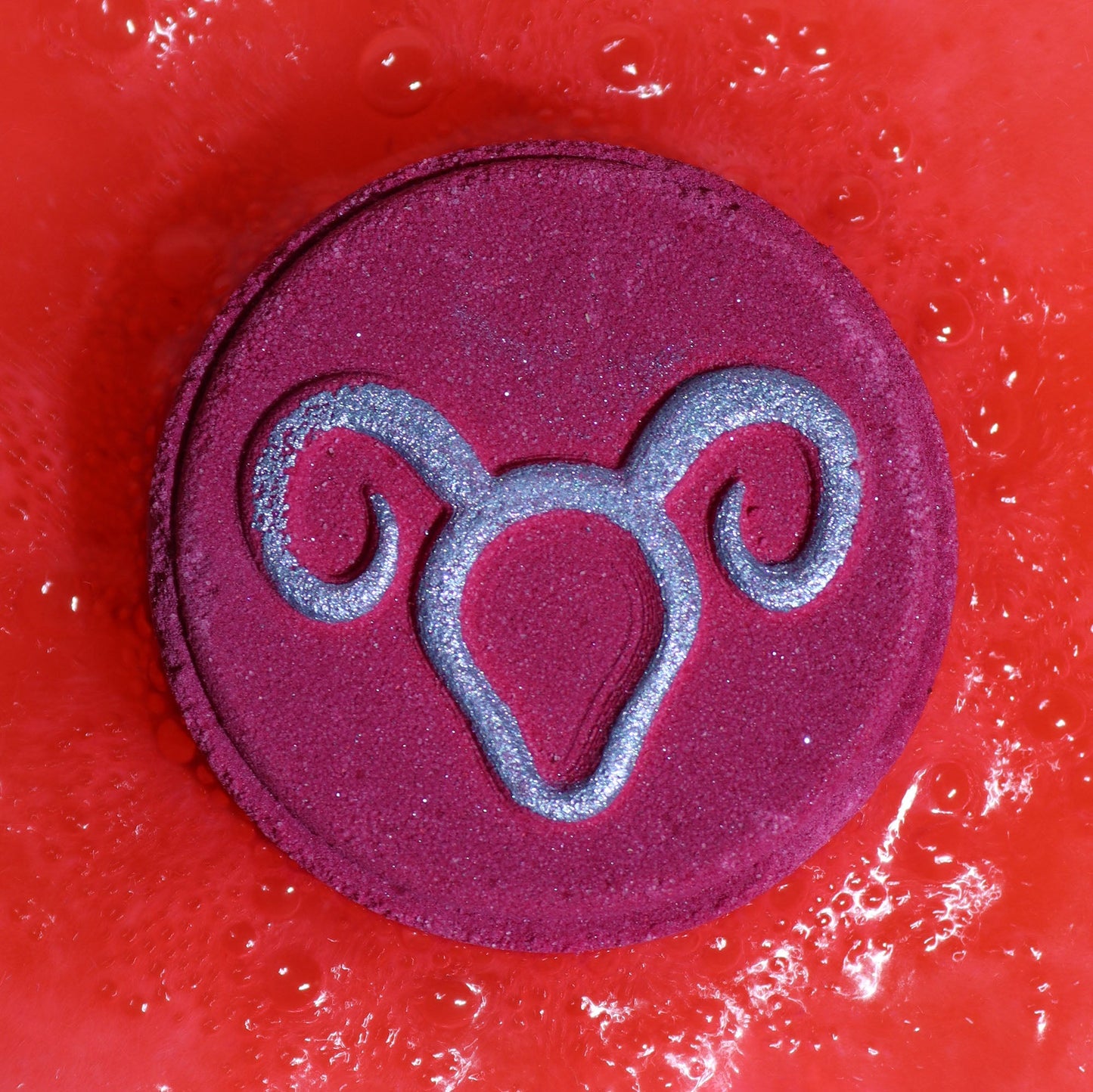 Aries Bath Bomb Fizzers - Clear Quartz Freshness - 2 Pack, close-up of a purple round fizzer embossed with the Aries symbol by Quintessential Holistic Health Ltd