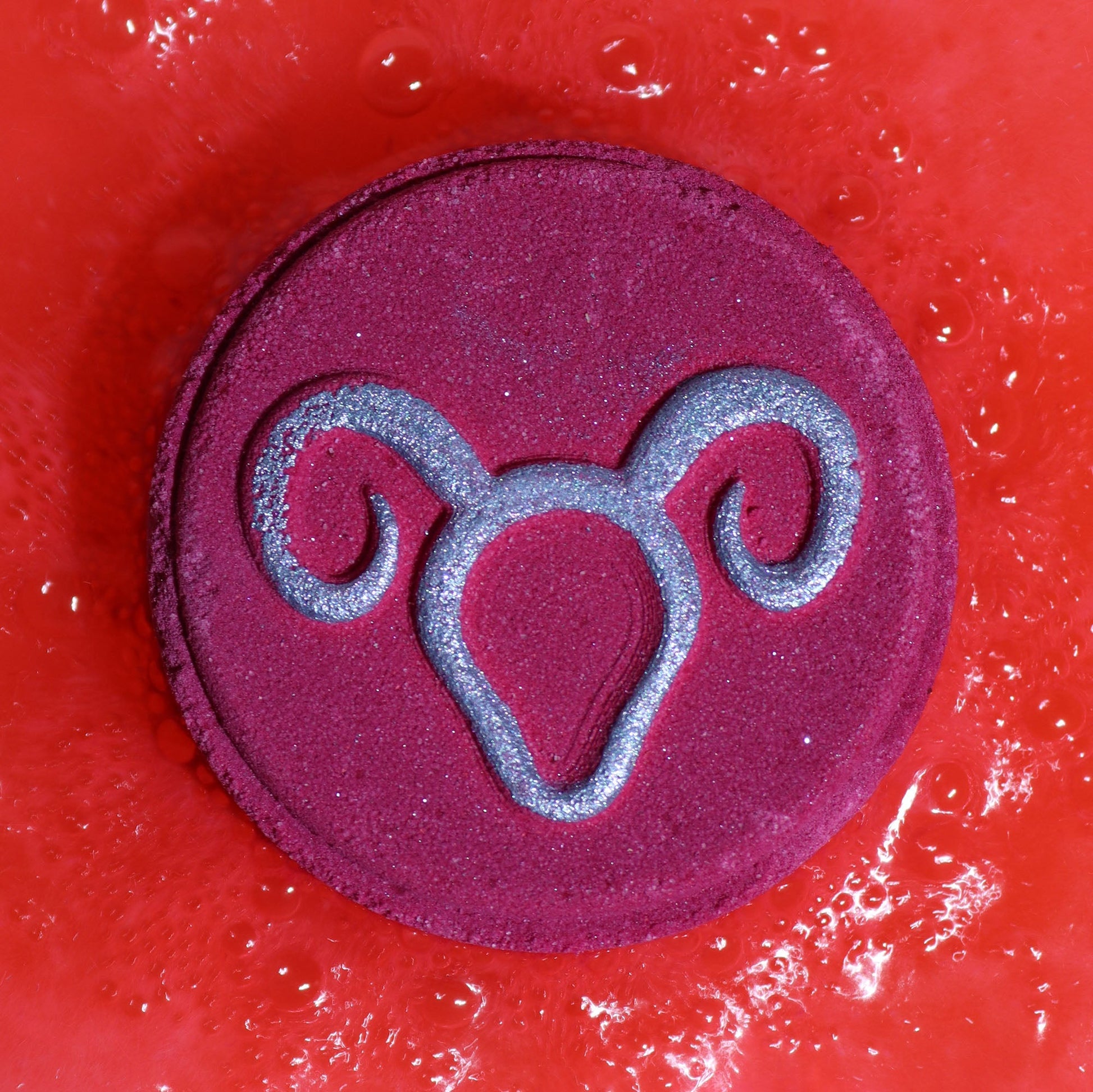 Aries Bath Bomb Fizzers - Clear Quartz Freshness - 2 Pack, close-up of a purple round fizzer embossed with the Aries symbol by Quintessential Holistic Health Ltd