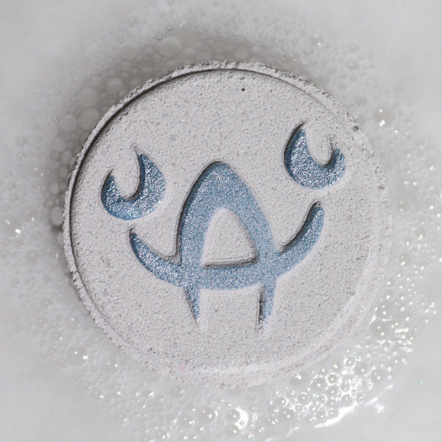 Cancer Bath Bomb Fizzers - Moonstone Eclipse - 2 Pack, close-up of a pale grey round fizzer embossed with the Cancer symbol by Quintessential Holistic Health Ltd